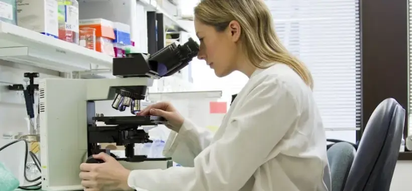 Une scientifique au microscope dans un laboratoire